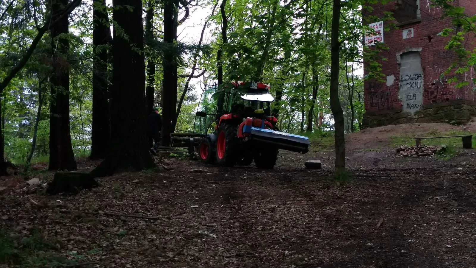 Ciągnik z kosiarką bijakową porządkuje zarośnięty teren przy wieży na Sołtysiej Górze