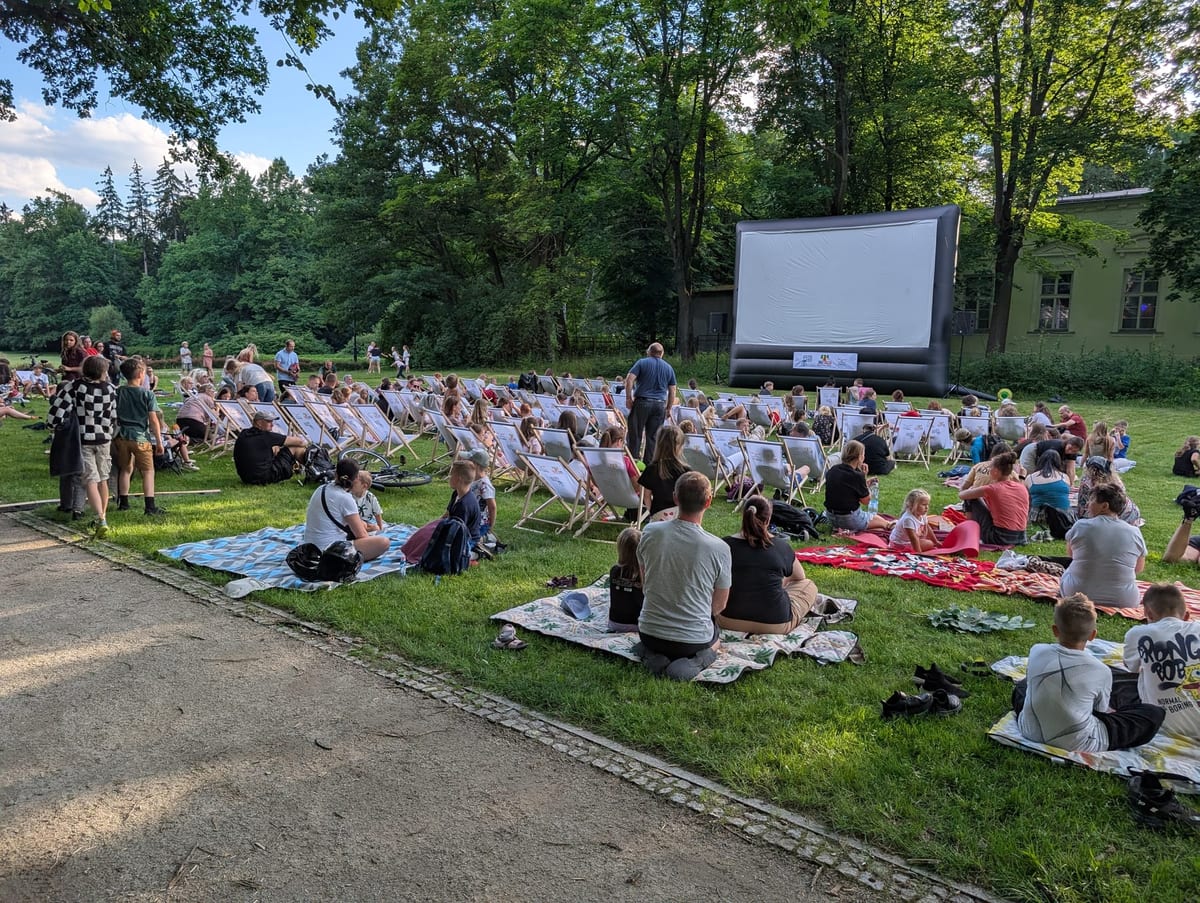 Widzowie na leżakach przed ekranem Letniego Kina pod Gwiazdami na polanie w Parku Zdrojowym